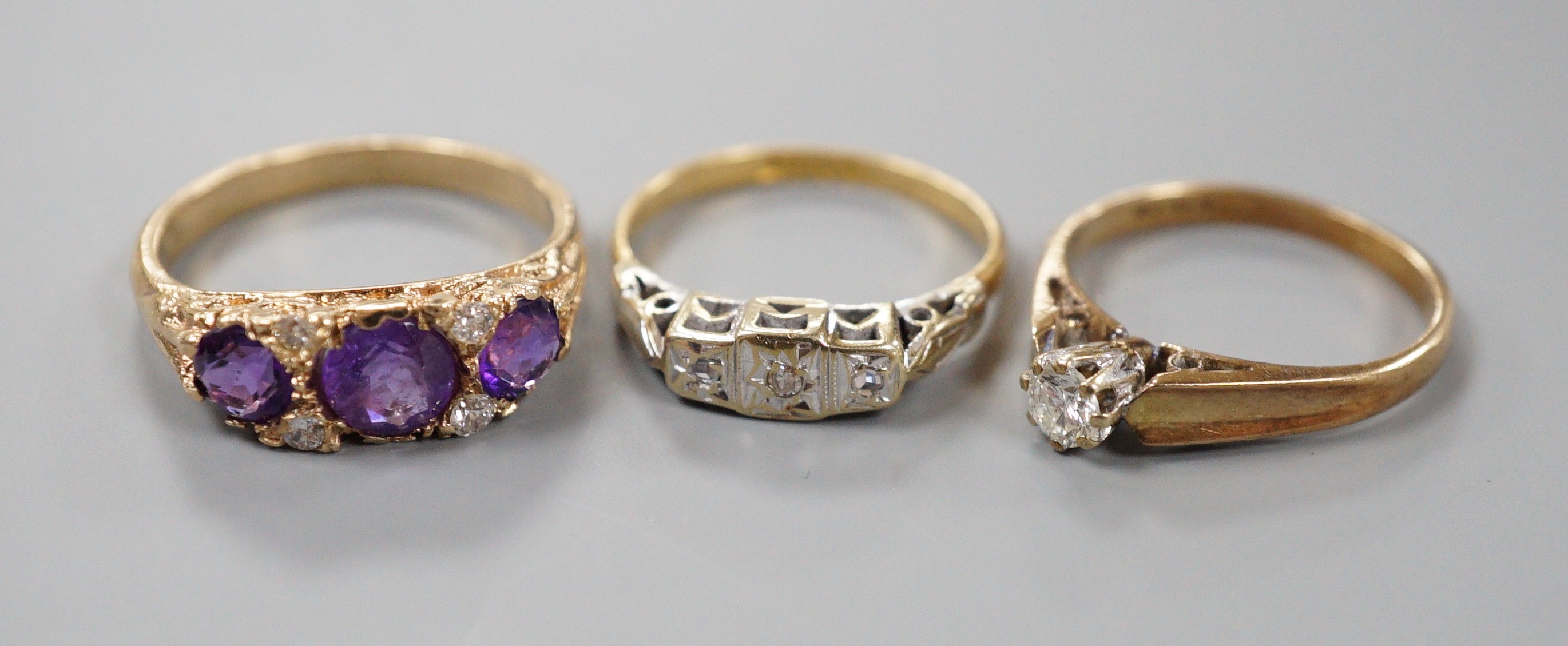 An 18ct and illusion set three stone diamond ring, gross 2.8 grams and two 9ct and gem set rings including amethyst and diamond chip half hoop, gross 5.2 grams.